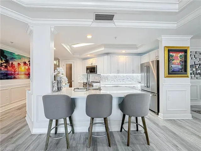 Kitchen featuring decorative backsplash, crown molding, appliances with stainless steel finishes, and light hardwood / wood-style flooring