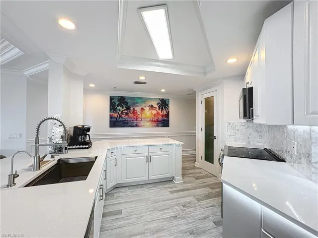 Kitchen with white cabinetry, tasteful backsplash, sink, light hardwood / wood-style floors, and kitchen peninsula