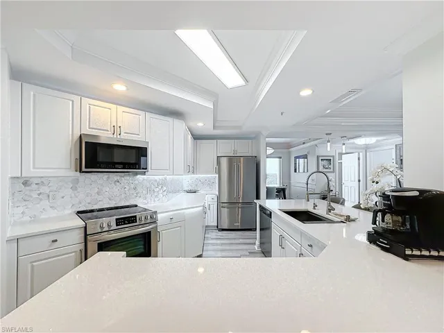 Kitchen with sink, appliances with stainless steel finishes, light wood-type flooring, and ornamental molding