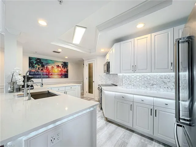 Kitchen featuring range with electric stovetop, light hardwood / wood-style floors, high end fridge, and kitchen peninsula