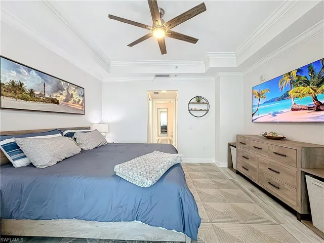 Bedroom featuring a raised ceiling, ornamental molding, and ceiling fan