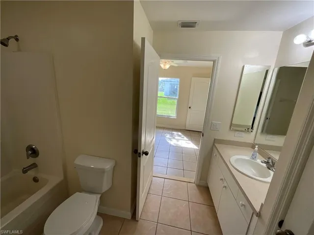 Full bathroom with tile patterned floors, shower / tub combination, vanity, toilet.
