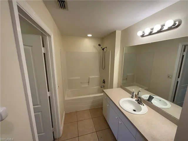 Bathroom with vanity, shower / washtub combination, and tile patterned flooring