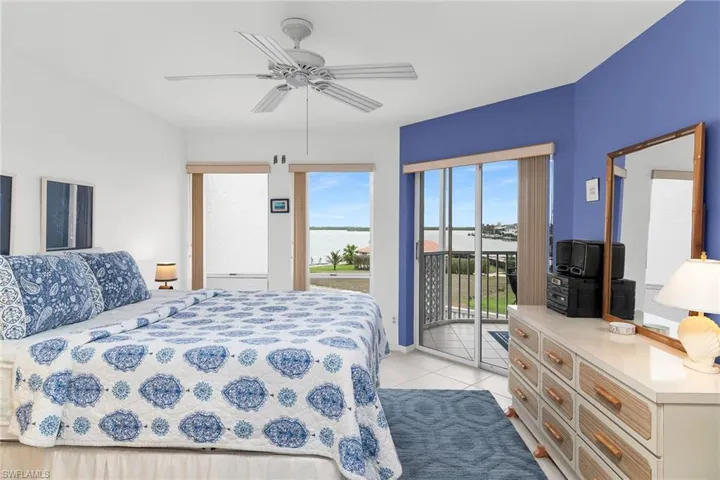 Bedroom featuring a water view, a ceiling fan, light tile patterned flooring, and access to exterior