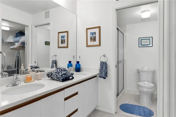 Bathroom with double vanity, a shower stall, and light tile patterned flooring