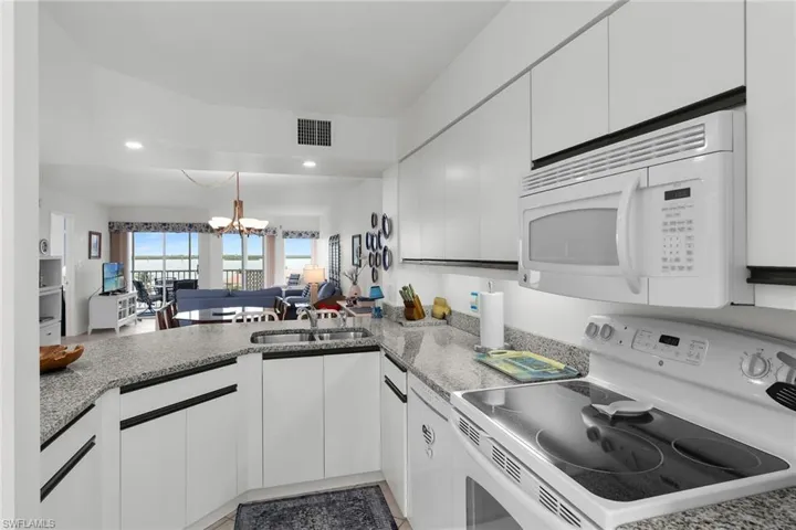 Kitchen featuring white appliances, a chandelier, open floor plan, and white cabinets