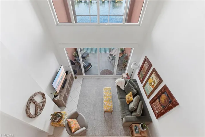 Living area featuring a double-height ceiling, upper-level windows, and a sliding glass door opening to an outdoor patio space