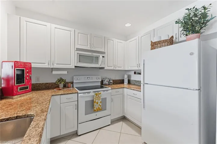 White kitchen featuring granite-style countertops, white cabinetry, a built-in microwave, and a white electric range