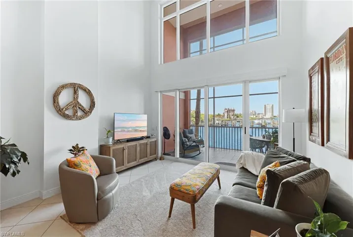 Bright living space featuring a two-story ceiling, a full wall of glass, and a sliding glass door opening to a private balcony