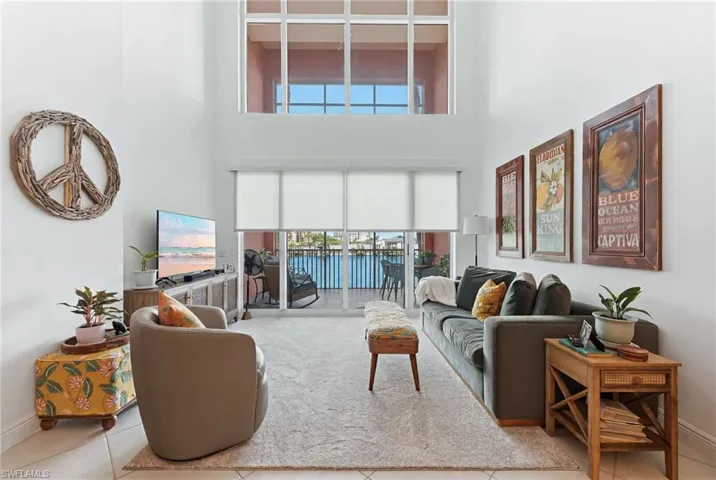 High ceilings framing a wall of windows, including upper transom windows, illuminate this living space