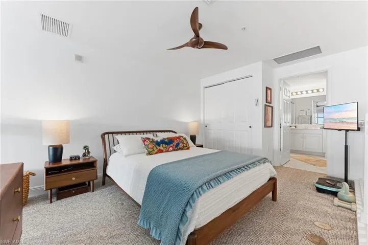 Spacious bedroom featuring light-colored carpeting, a contemporary ceiling fan, and bi-fold closet doors
