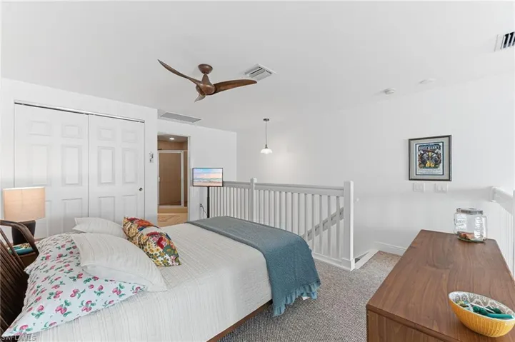 Open loft area featuring neutral carpeting, a ceiling fan, and white painted walls