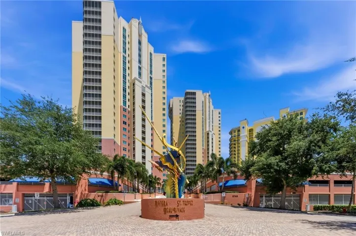 High-rise building exterior featuring multiple balconies, a decorative water feature, and mature trees