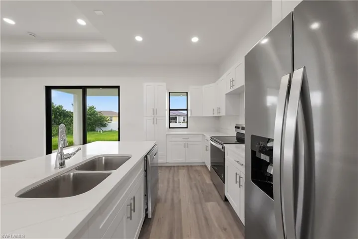 Kitchen featuring stainless steel appliances, recessed lighting, light wood-style floors, white cabinets, and light stone countertops