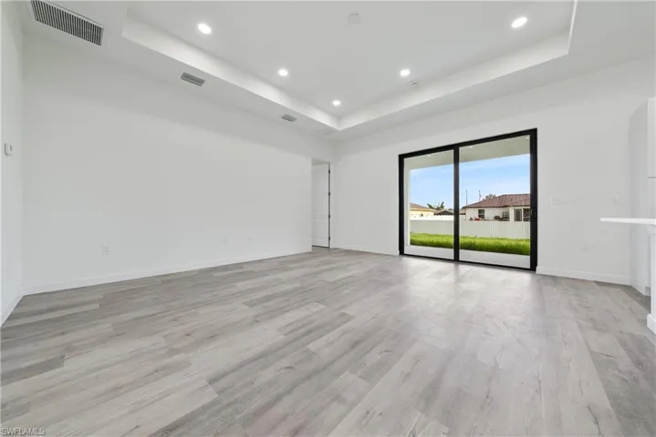 Unfurnished room featuring a raised ceiling, recessed lighting, and light wood-style flooring