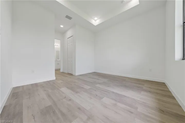 Spare room with light wood-type flooring, recessed lighting, and a raised ceiling
