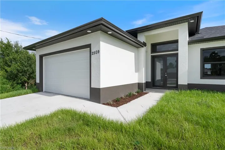 View of front of property featuring an attached garage, french doors, stucco siding, and driveway