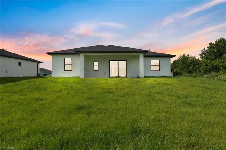 Rear view of property featuring stucco siding and a yard