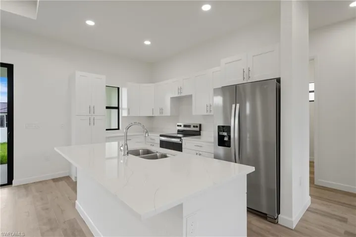 Kitchen featuring appliances with stainless steel finishes, recessed lighting, white cabinetry, a center island with sink, and light wood-type flooring