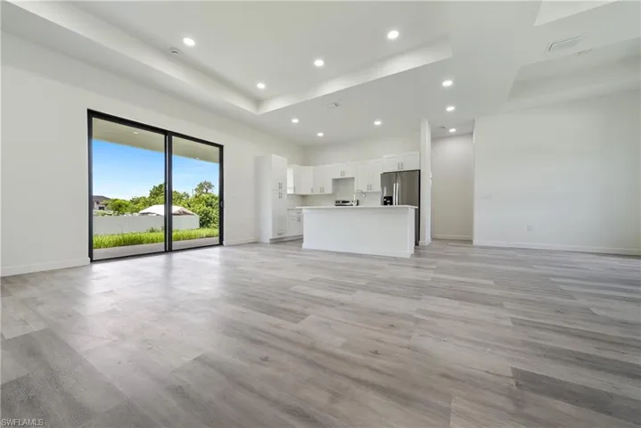 Unfurnished living room with a tray ceiling, recessed lighting, and light wood-style flooring