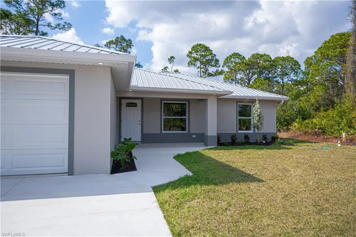 View of exterior entry with a yard, a metal roof, stucco siding, and a porch