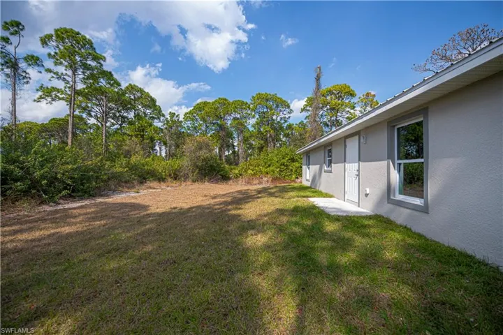 View of green lawn featuring a patio area and view of scattered trees