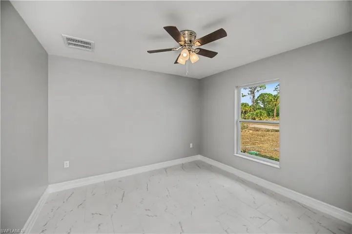 Empty room with light marble finish flooring and a ceiling fan