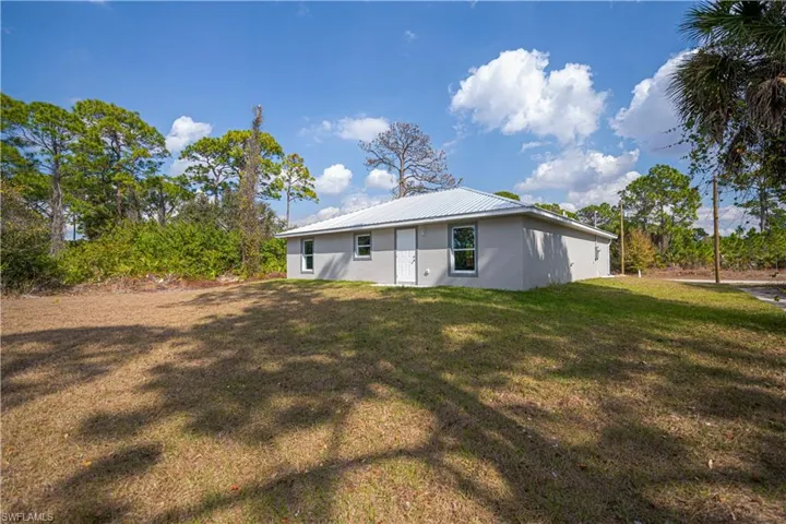 Back of house featuring a yard, stucco siding, and a metal roof