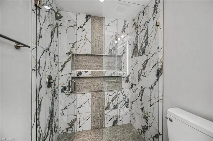 Full bathroom featuring a marble finish shower and toilet