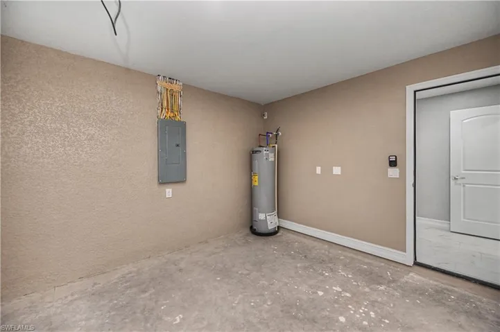 Utility room featuring electric panel and electric water heater