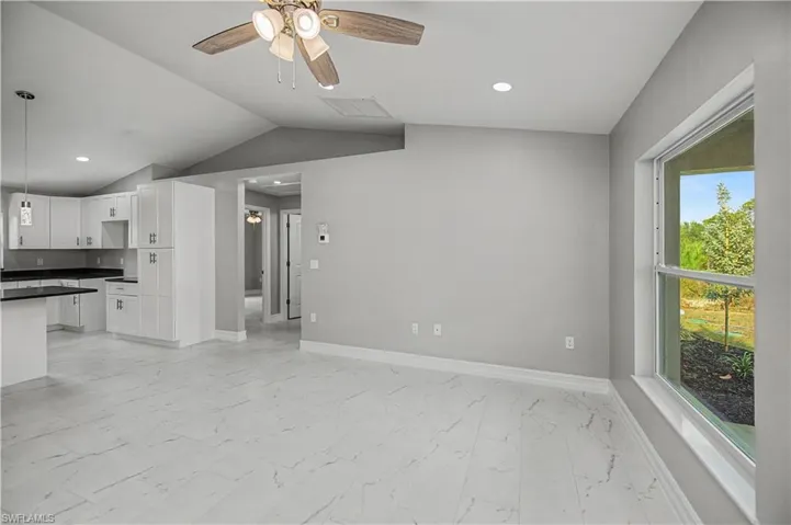 Unfurnished living room with lofted ceiling, recessed lighting, a ceiling fan, and light marble finish floors
