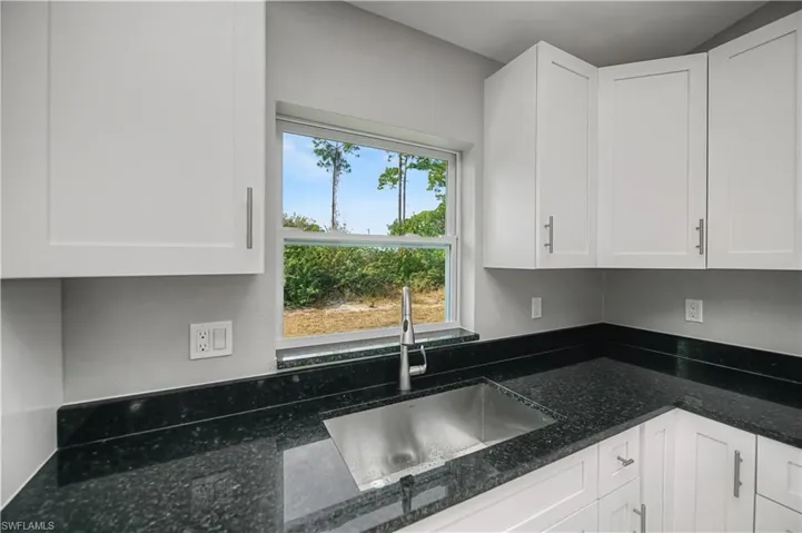 Kitchen featuring dark stone countertops and white cabinets