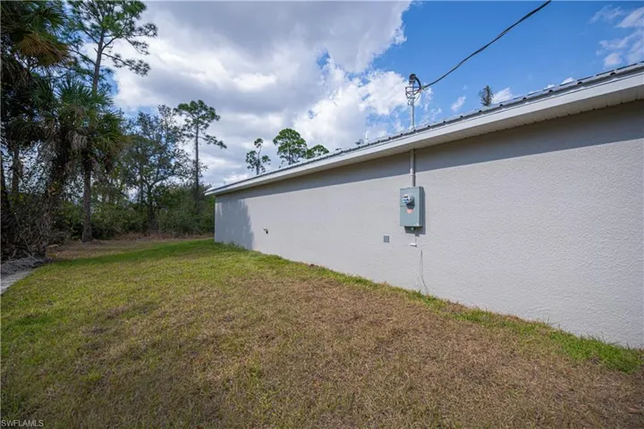 View of side of property with a lawn and stucco siding