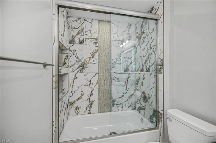 Full bath with enclosed tub / shower combo and toilet