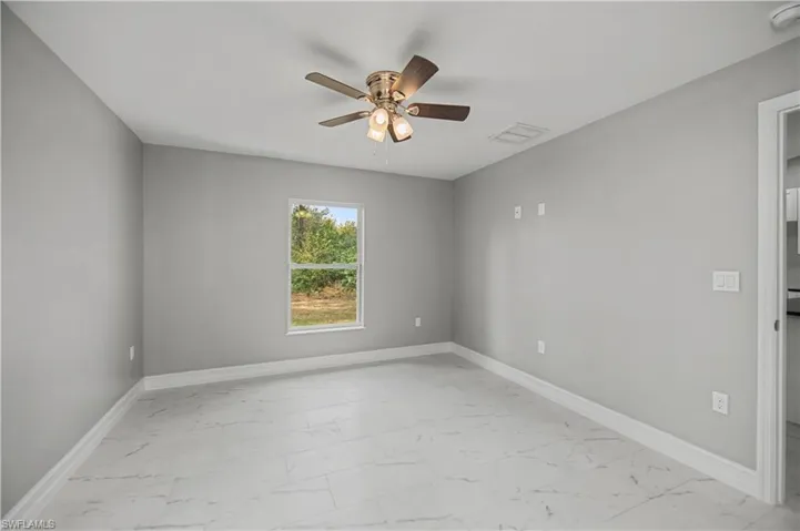 Empty room featuring light marble finish floors and a ceiling fan