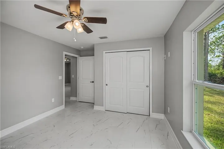 Unfurnished bedroom with light marble finish floors, a ceiling fan, and a closet