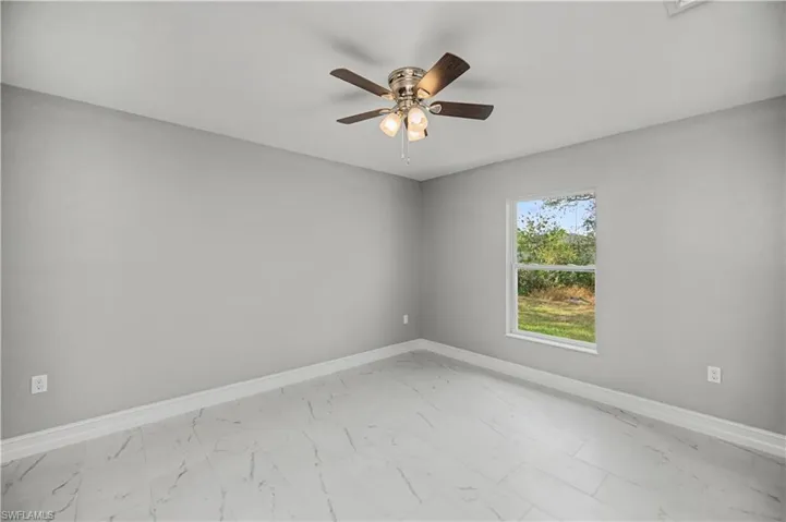 Unfurnished room featuring light marble finish flooring and ceiling fan