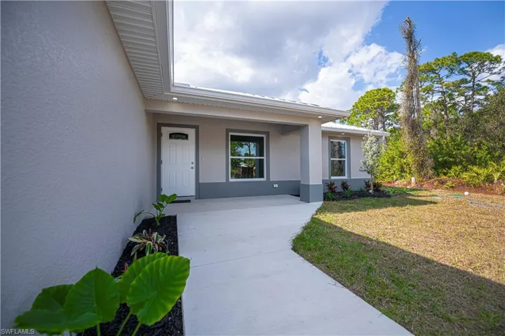 Property entrance with a yard, stucco siding, and a porch