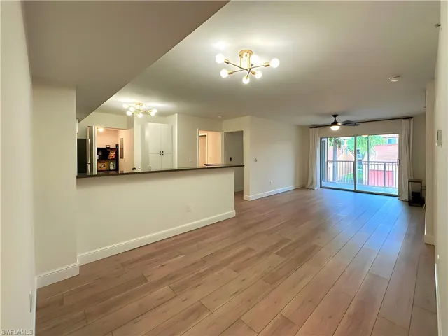 Unfurnished living room featuring ceiling fan with notable chandelier and light wood-type flooring