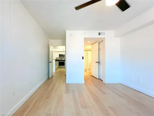 Unfurnished bedroom featuring connected bathroom, light hardwood / wood-style floors, and ceiling fan