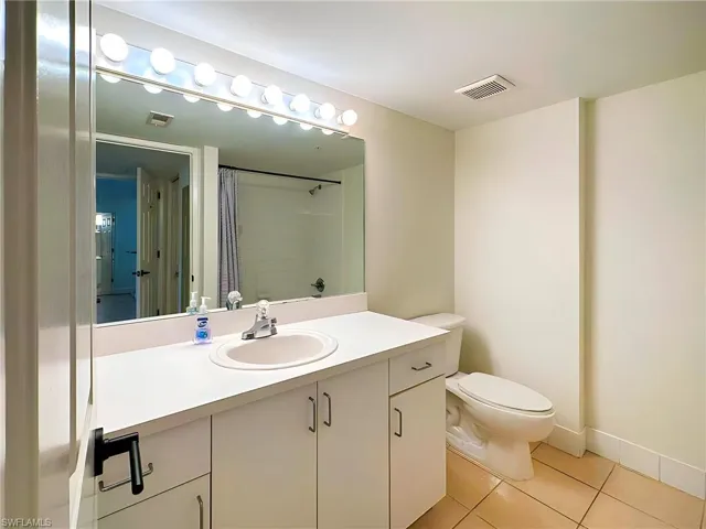 Bathroom with vanity, toilet, tile patterned flooring, and a shower with shower curtain