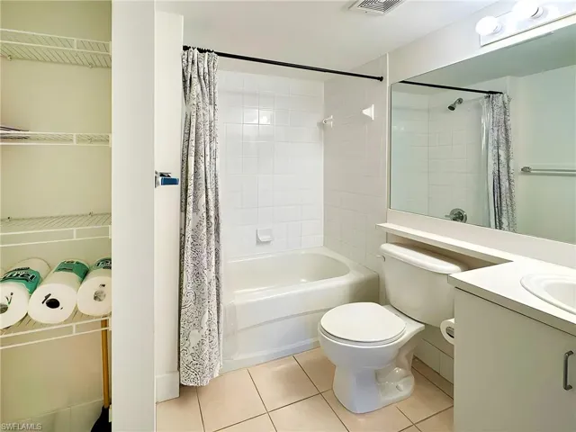 Full bathroom with vanity, toilet, tile patterned floors, and shower / bath combination with curtain