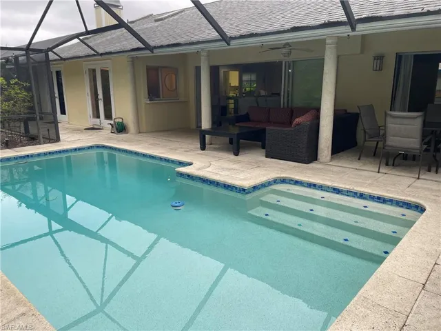 Outdoor pool with a patio area, an outdoor hangout area, and a ceiling fan