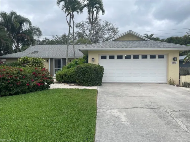 Single story home featuring a shingled roof, driveway, a front lawn, and stucco siding