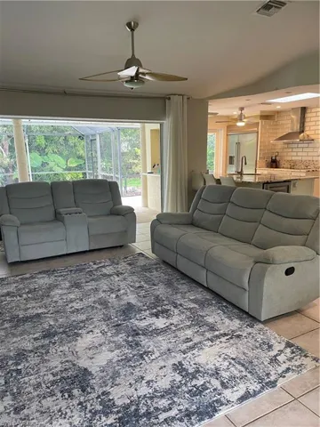 Living room with light tile patterned floors, ceiling fan, and visible vents
