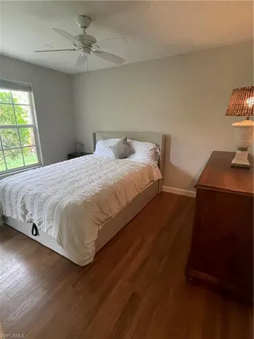 Bedroom with a ceiling fan, dark wood finished floors, and baseboards
