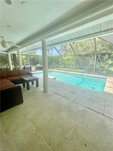 Outdoor pool with a ceiling fan, glass enclosure, and a patio