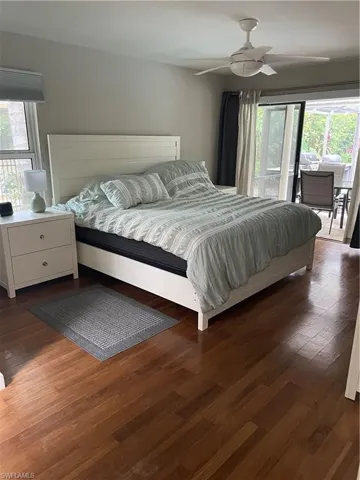 Bedroom featuring dark wood-style floors, access to outside, multiple windows, and a ceiling fan