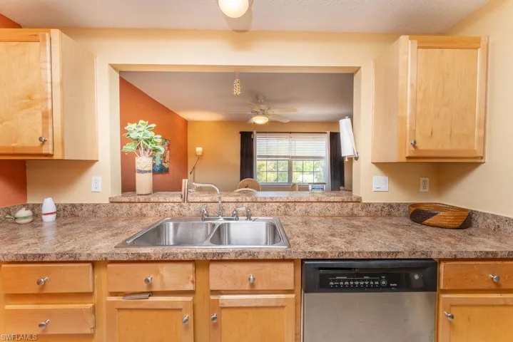 Kitchen with dishwasher, light brown cabinetry, light countertops, and a ceiling fan