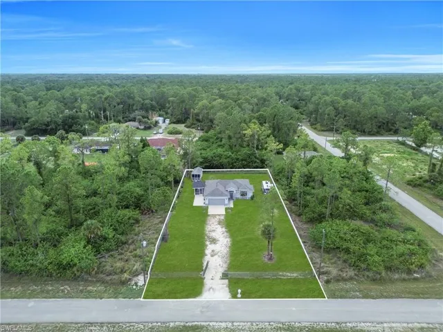 Property featuring a contemporary ranch-style home with a gray exterior, a paved driveway, and a verdant lawn
